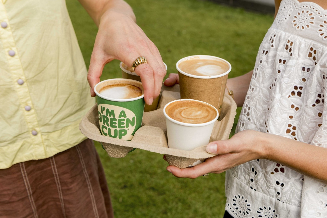 4 cup coffee cup carrier with 3 single wall coffee cups inside being shared out to friends in a park