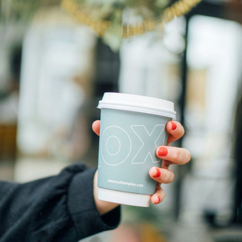 custom printed coffee cup with a white lid being held by a customer