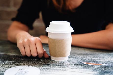 single wall aqueous coffee cup with cardboard cup sleeve and white bagasse compostable lid