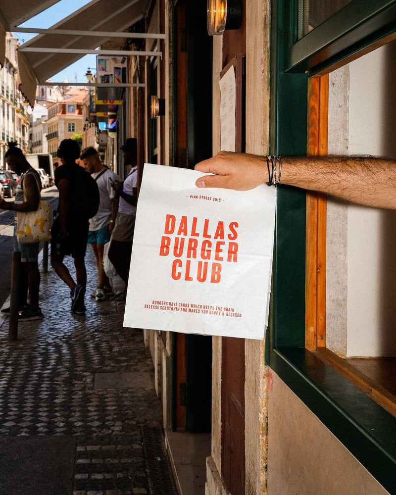 custom printed takeaway paper bag being held out of a window