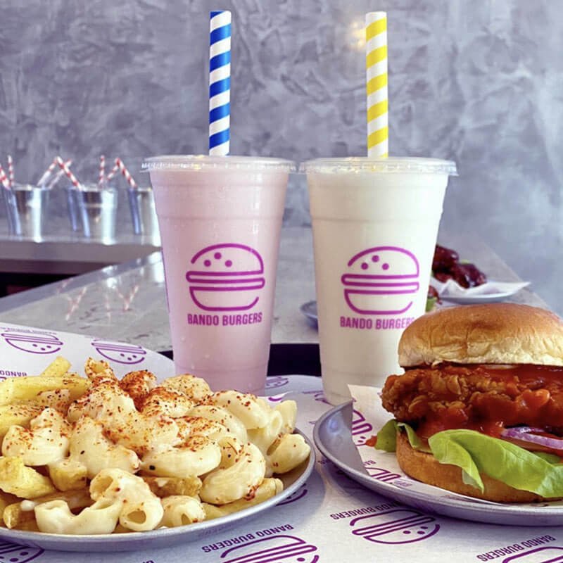 16oz custom printed milkshake cups with lids and paper straws on a table with food and printed greaseproof paper