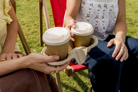 two friends sharing coffees in kraft compostable coffee cups with white pla lids in a bagasse two cup carrier