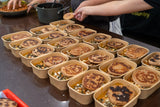 rectangular kraft containers lined up on a counter ready to serve multiple takeout meals