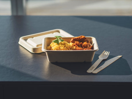 rectangular takeaway container and lid with wooden cutlery serving chicken curry and rice