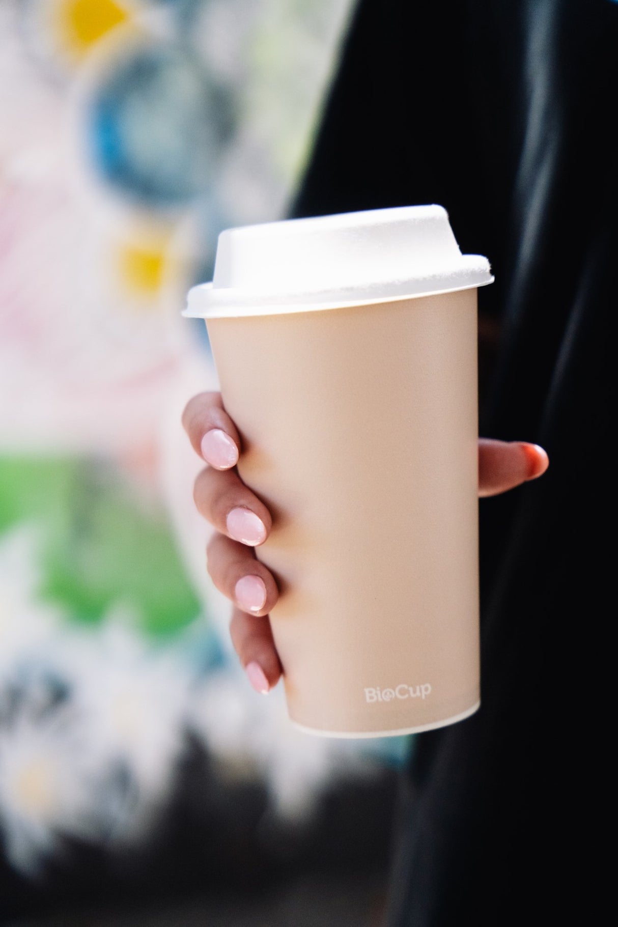 single wall aqueous coffee cup with bagasse lid in a womans hand