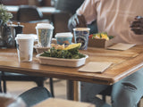 single wall art series coffee cups with a rectangular takeaway container on a table in a restaurant