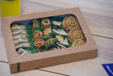 a kraft grazing platter box containing sandwiches and small pastries seen through a compostable pla window